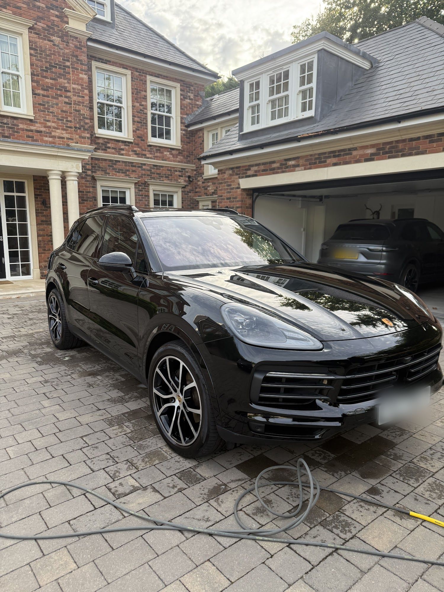 Black Porsche Cayenne after a Montagna detail, on a block-paved driveway